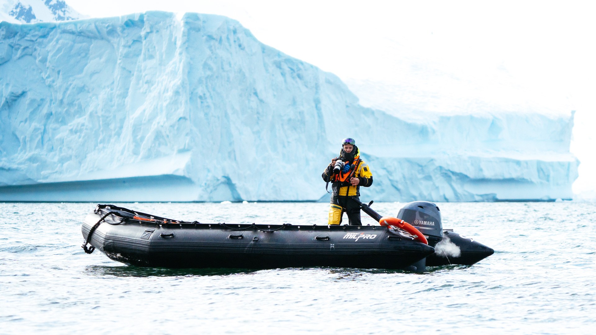 Photographer working from a zodiac beside an Antarctic iceberg